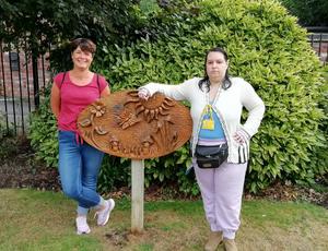 Image of wooden carved nature scene plaque with two women volunteers from Dawley Sculpture Park group