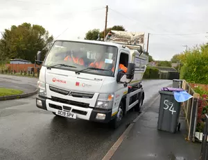 image of truck on residential roads with bins on the pavement