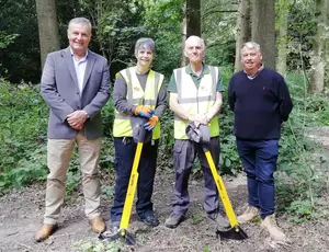 Photo showing volunteers Julie and Chris each holding a tree popper tool (which are a yellow metal rod 1 metre tall with a black semi circular part on the end), in Apley Woods with Councillor Overton and Ian Hancock from Veolia