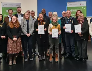 Image showing thirty people grouped together facing the camera, some with certificates. Amongst them is the mayor. In the background are branded EnviroGrant banners.