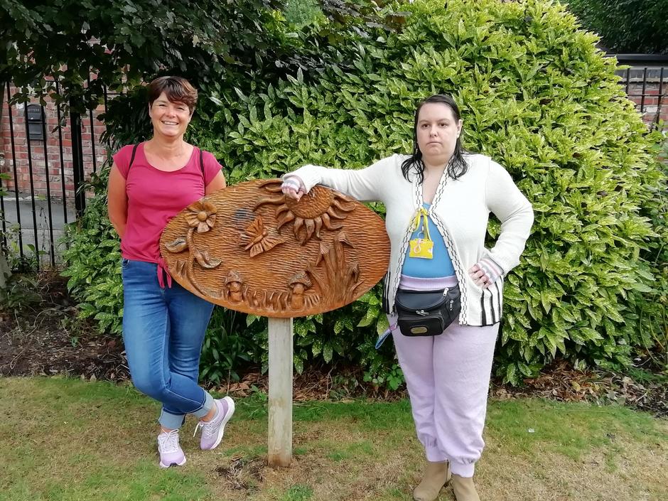 Image of wooden carved nature scene plaque with two women volunteers from Dawley Sculpture Park group