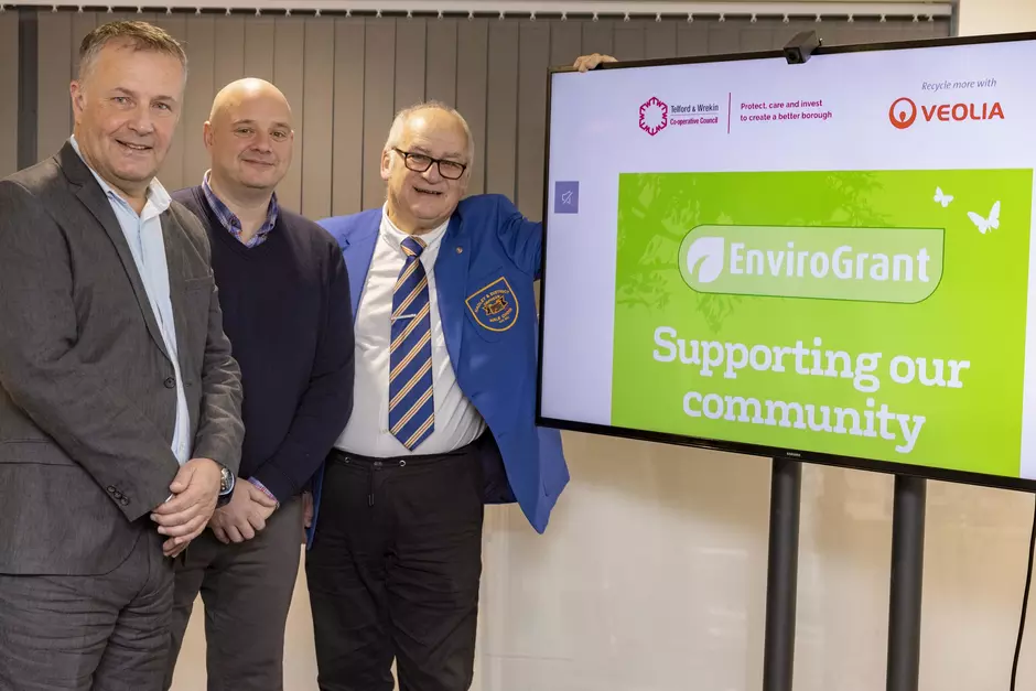 Photo of a grant recipient with representatives from Veolia and Telford & Wrekin Council next to a green EnviroGrant logo