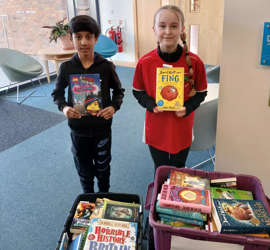 PHoto shows two pupils at Lightmoor Village Primary with their free books in hand and boxes of books around them