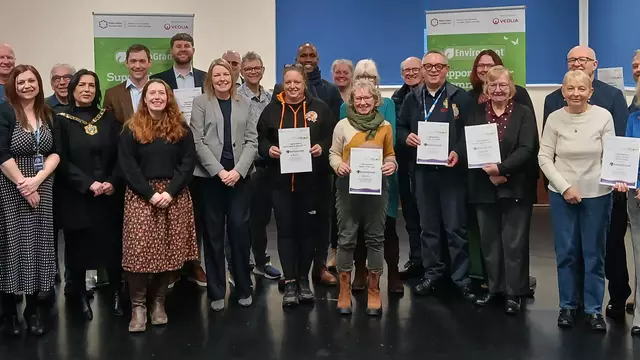Image showing thirty people grouped together facing the camera, some with certificates. Amongst them is the mayor. In the background are branded EnviroGrant banners.