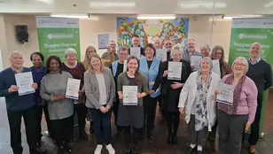 Photo showing a large group of people with grant certificates, in a community hall with EnviroGrant branded banners in the background
